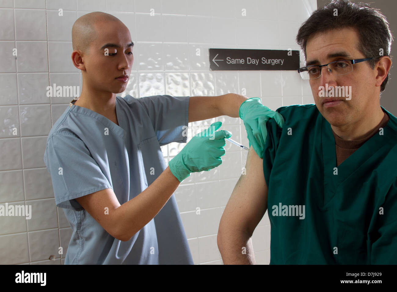 Health care professional administering vaccination to fellow staff member Stock Photo
