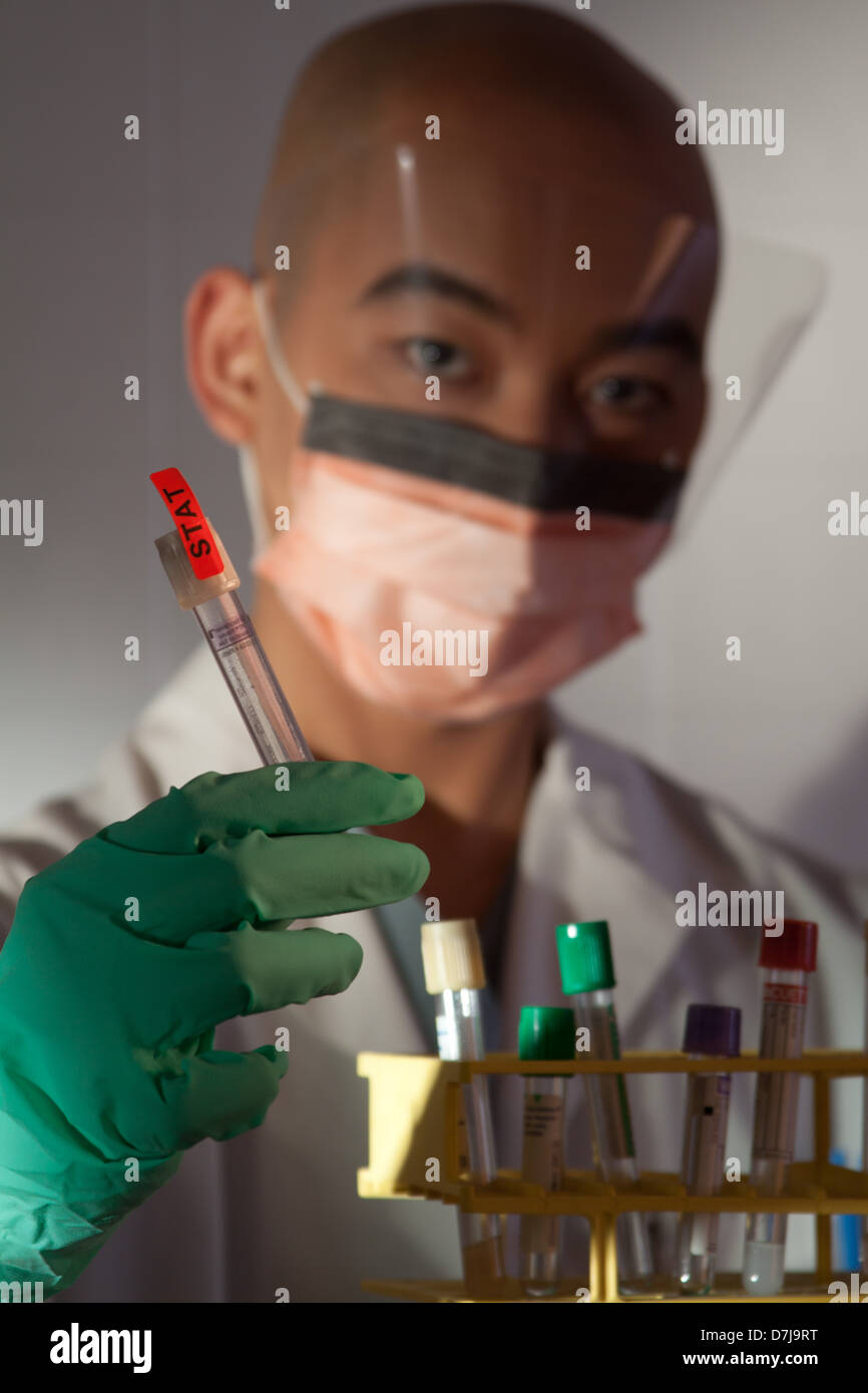 Lab tech holding test tube. Focus on the test tube in the foreground Stock Photo