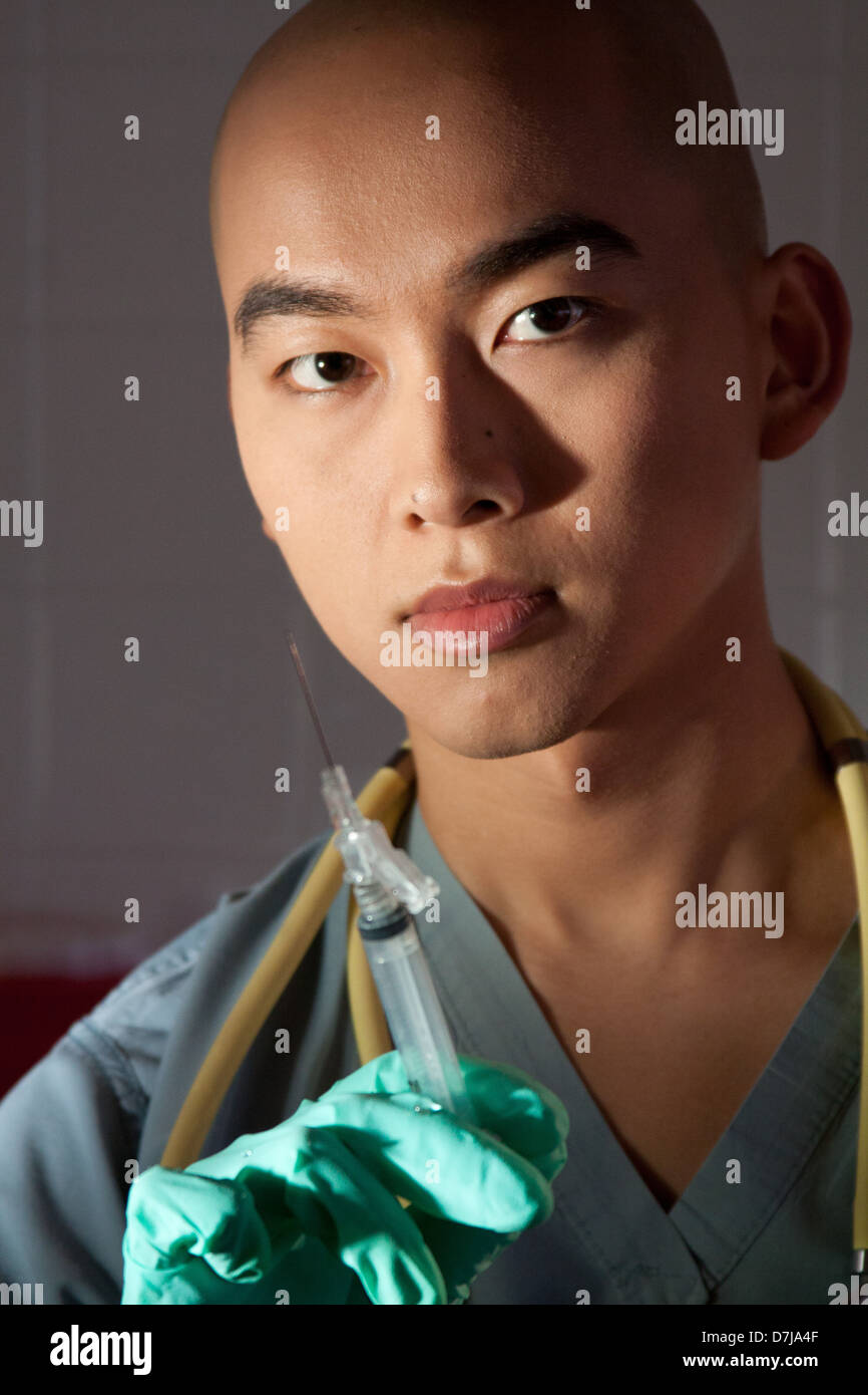 Nurse holding syringe in gloved hand, portrait Stock Photo