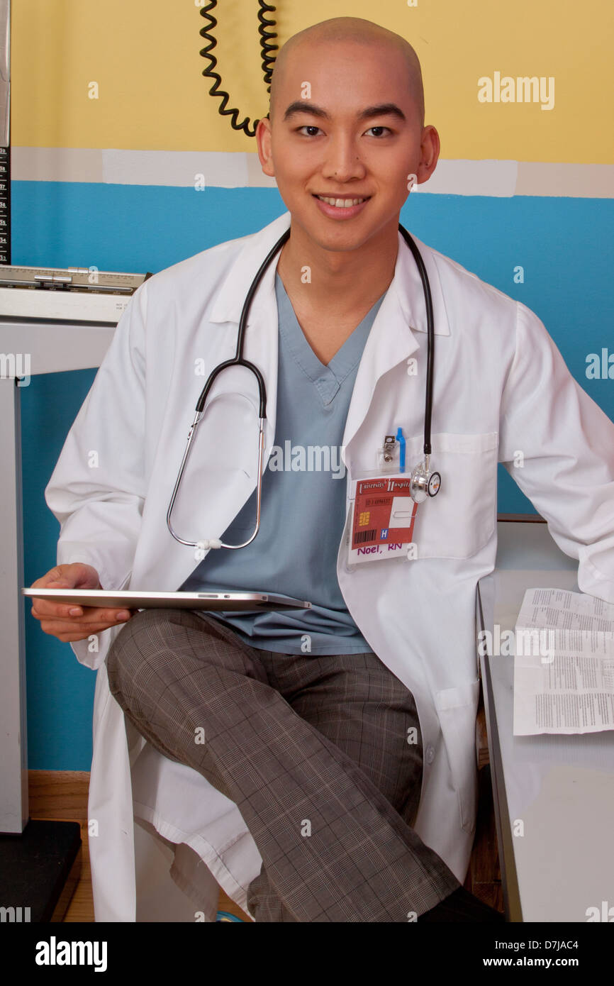 Portrait of doctor sitting in exam room reviewing new drug information on a tablet Stock Photo