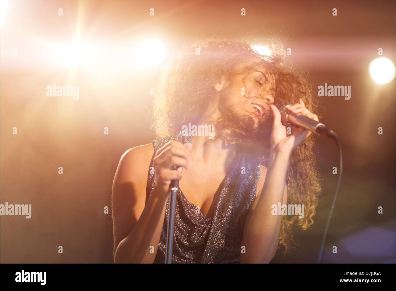 Young woman singing in spotlight Stock Photo