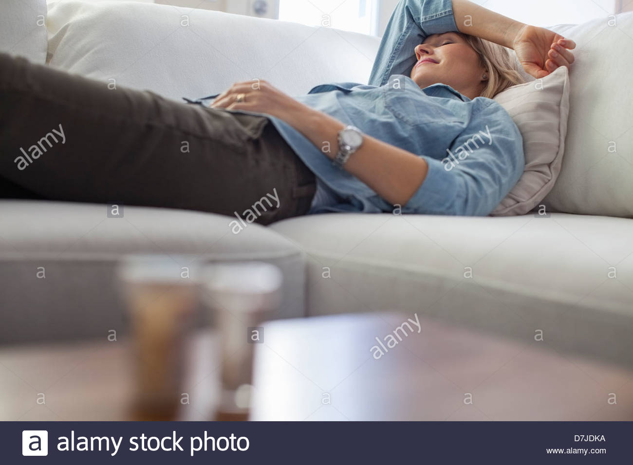Woman with headache sleeping on sofa Stock Photo