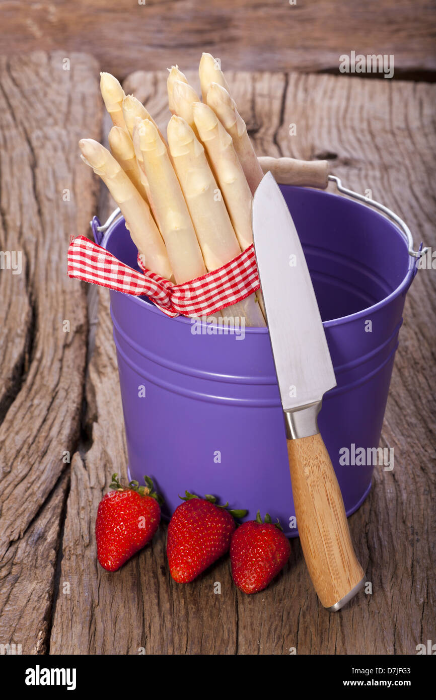 Fresh asparagus in a colorful metal buckets before a knife and three