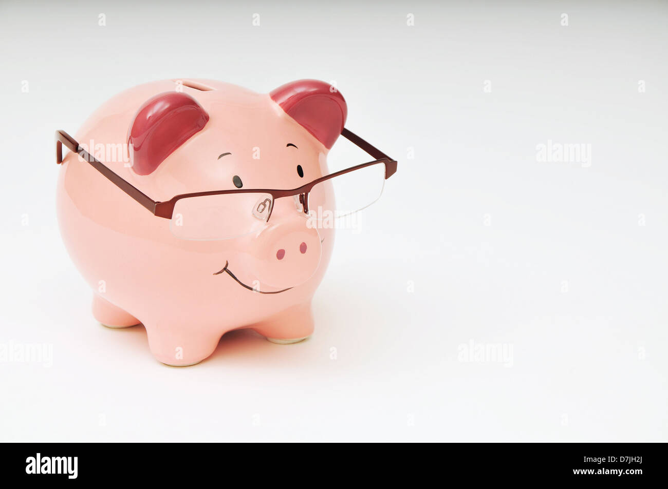 Smiling pink piggy bank wearing glasses against a white background ...