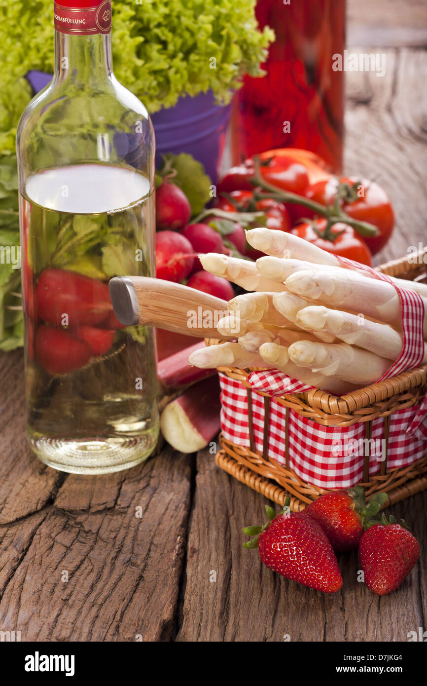 Fresh fruit and vegetables of the season with asparagus, rhubarb and wine bottles on a rustic wooden background Stock Photo