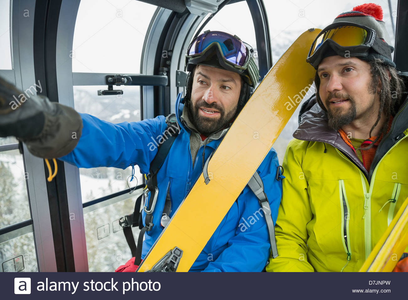 Male skiers talking in gondola in mountains Stock Photo