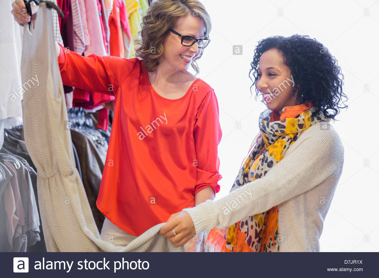 Female small business owner assisting customer with clothing choice