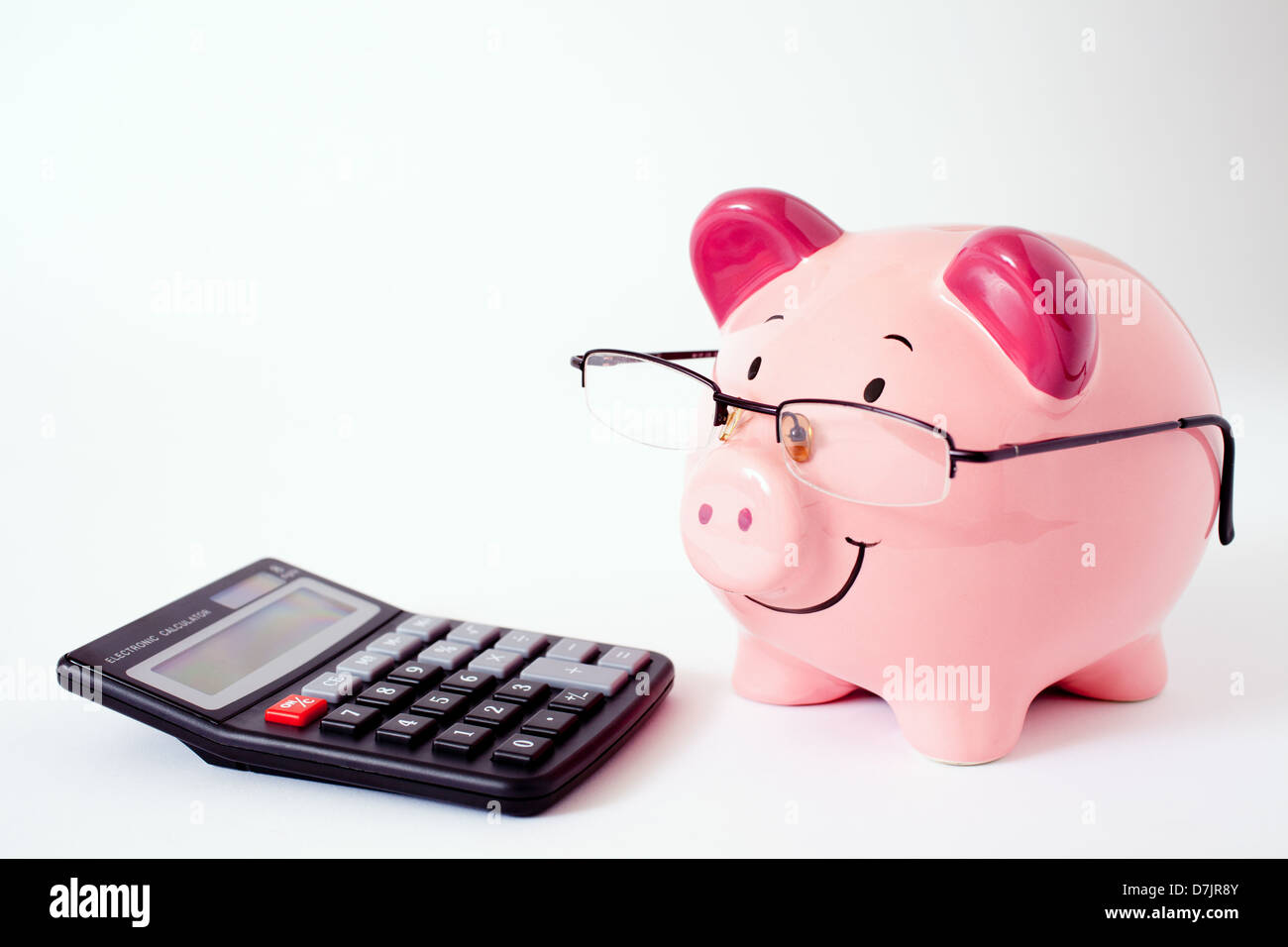 Smiling pink piggy bank wearing glasses with a calculator in front ...