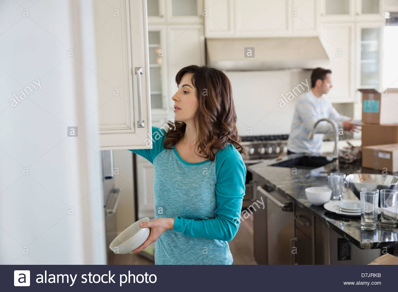 Couple putting away dishes in new home Stock Photo