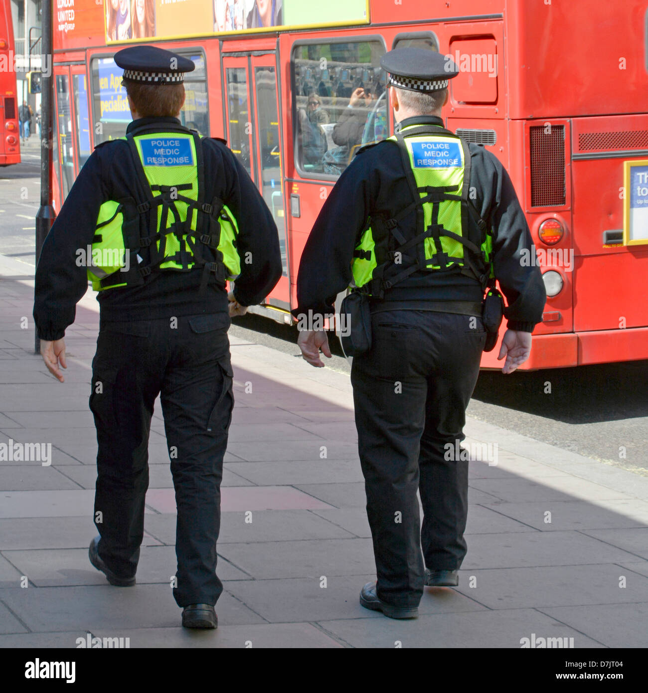 Close up back view of two medic response police officers in uniform back packs on Metropolitan policemen on foot patrol West End London England UK Stock Photo