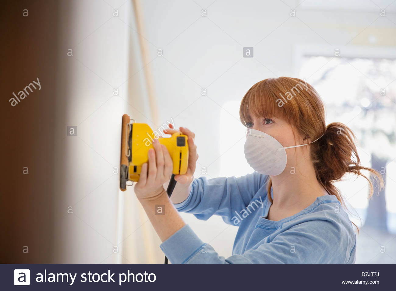 Woman wearing mask sanding wall in home Stock Photo Alamy