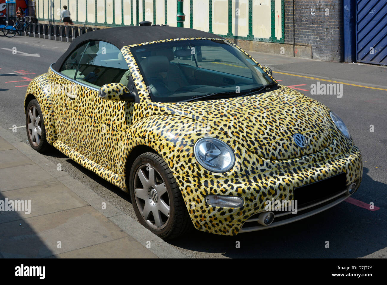 Leopards skin print covers bodywork of Volkswagen VW Beetle car  with black vinyl roof parked in sunny Brick Lane Tower Hamlets East London England UK Stock Photo