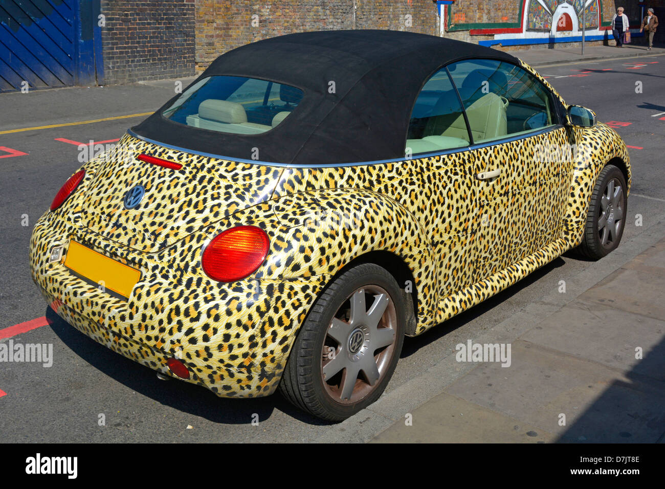 Leopard skin print covers bodywork of Volkswagen VW Beetle car  with black vinyl roof parked in sunny Brick Lane Tower Hamlets East London England UK Stock Photo