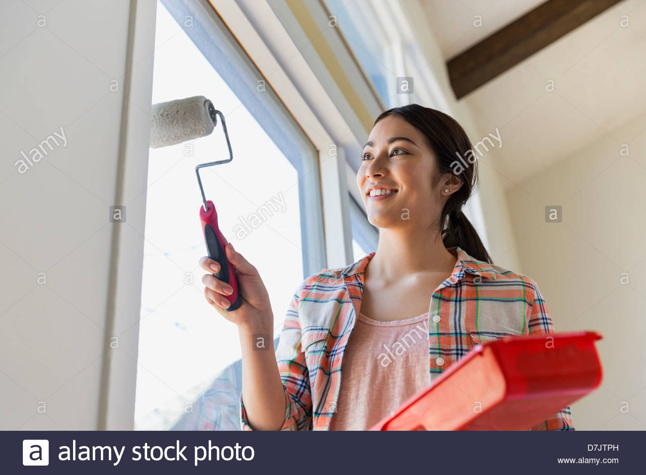 Young woman painting wall at home Stock Photo