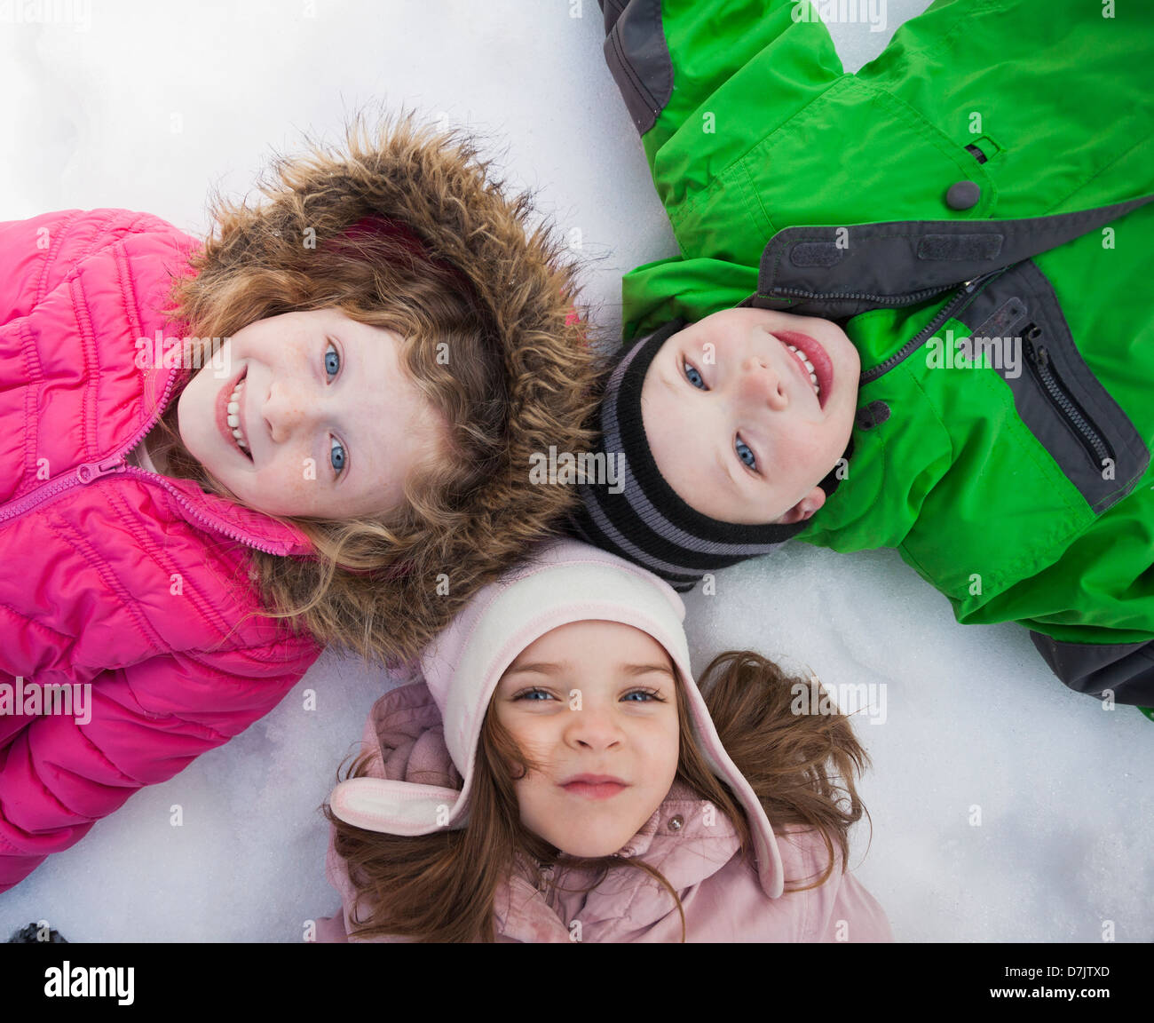 Directly above portrait of three children (2-3, 4-5) lying on snow Stock Photo