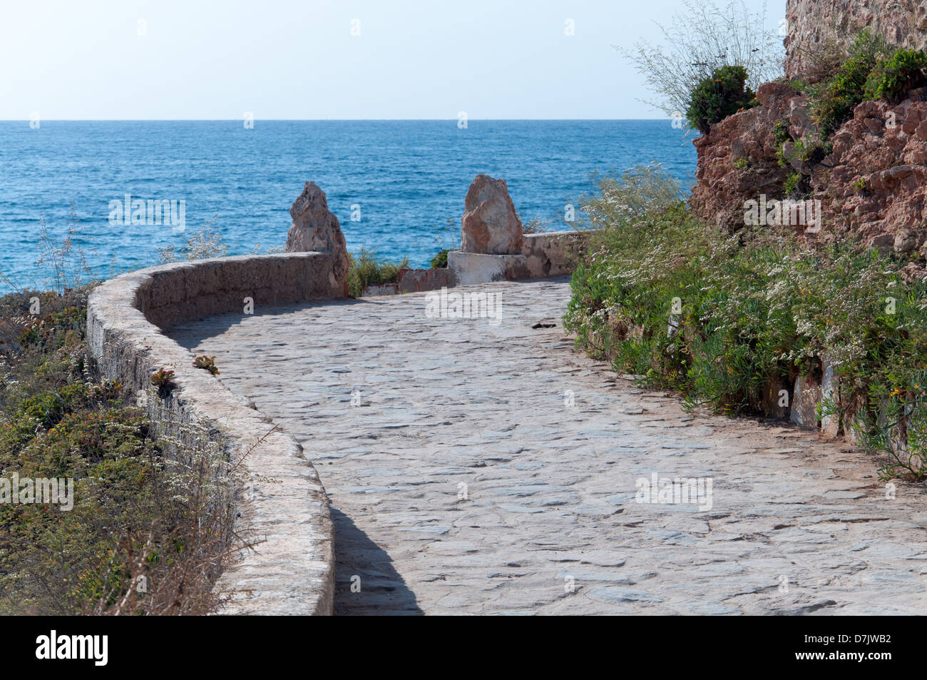 Curved path with cobble stones along the Mediterranean sea. Stock Photo
