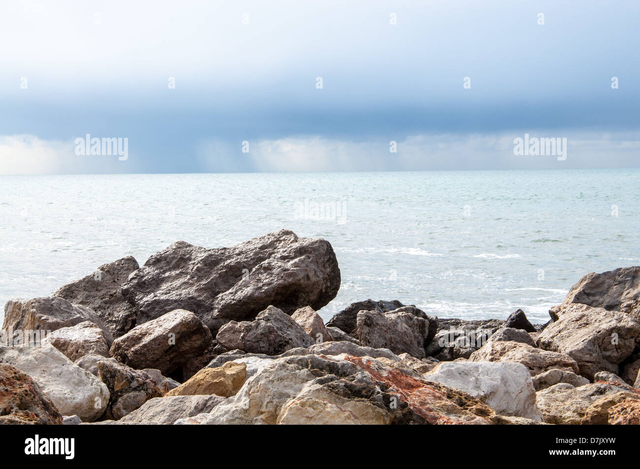 Rocks, ocean and rains leaving the bay. Stock Photo