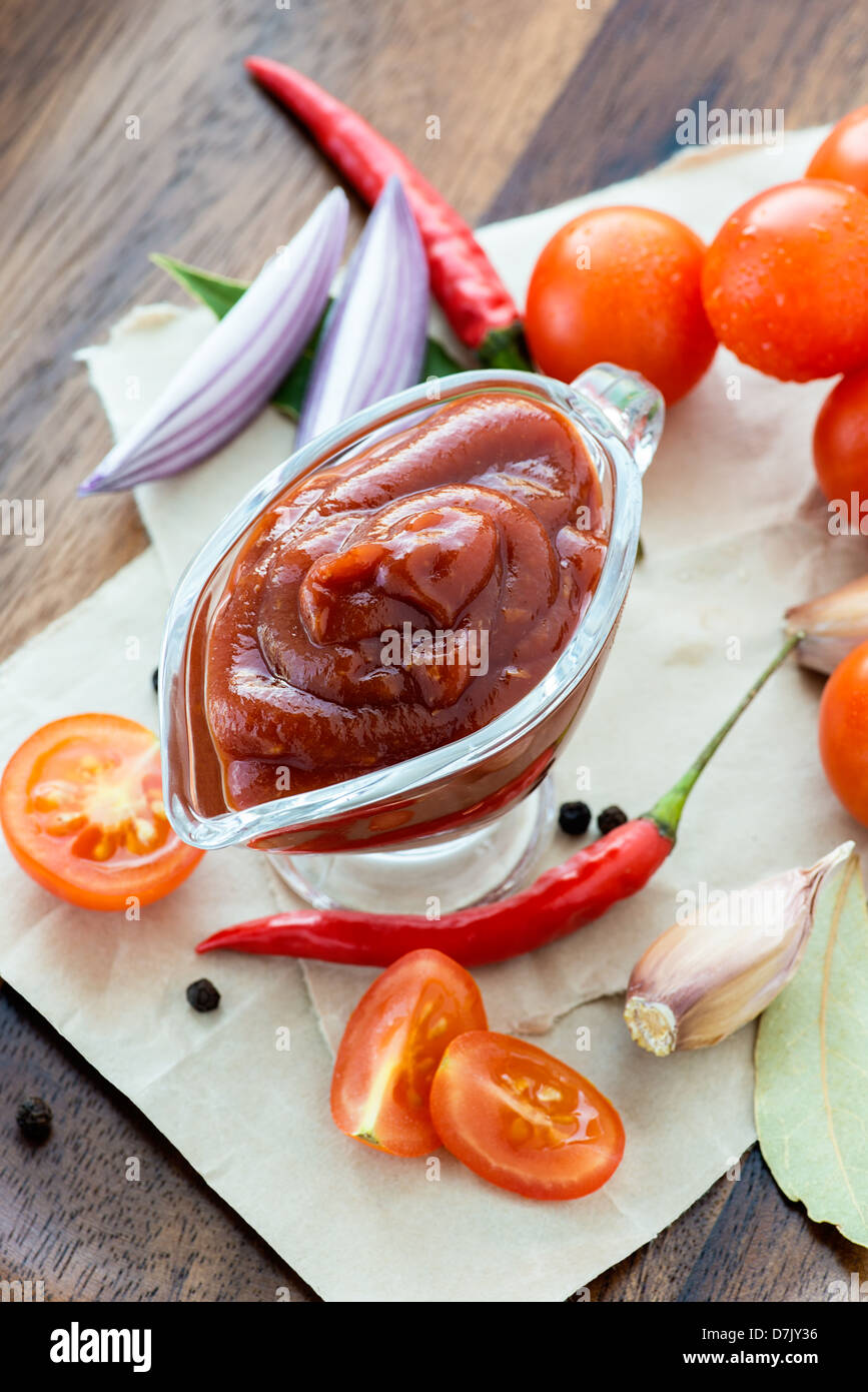 Traditional homemade tomato sauce with ingredients on wooden background