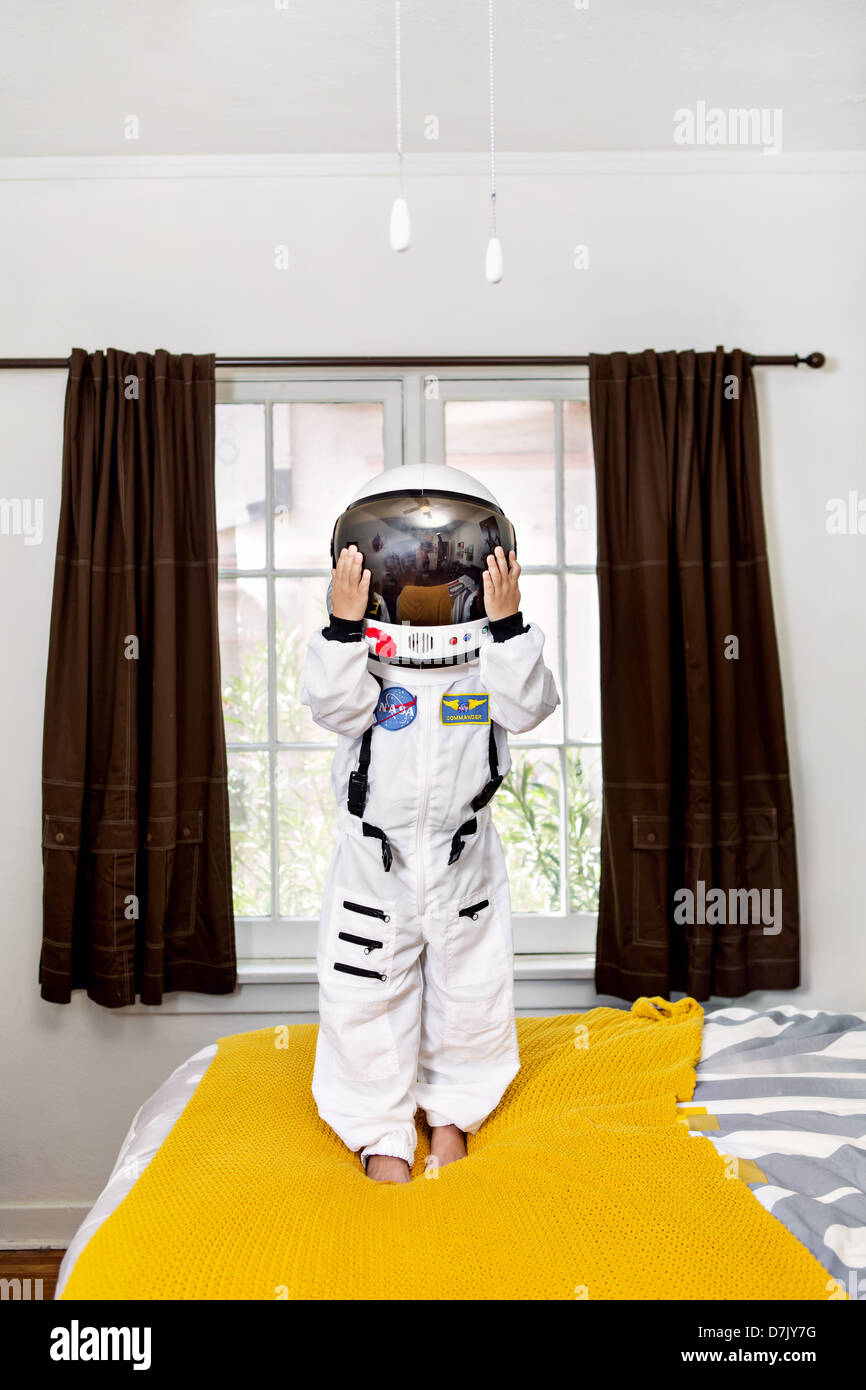 portrait of boy standing on his bed in space suit Stock Photo