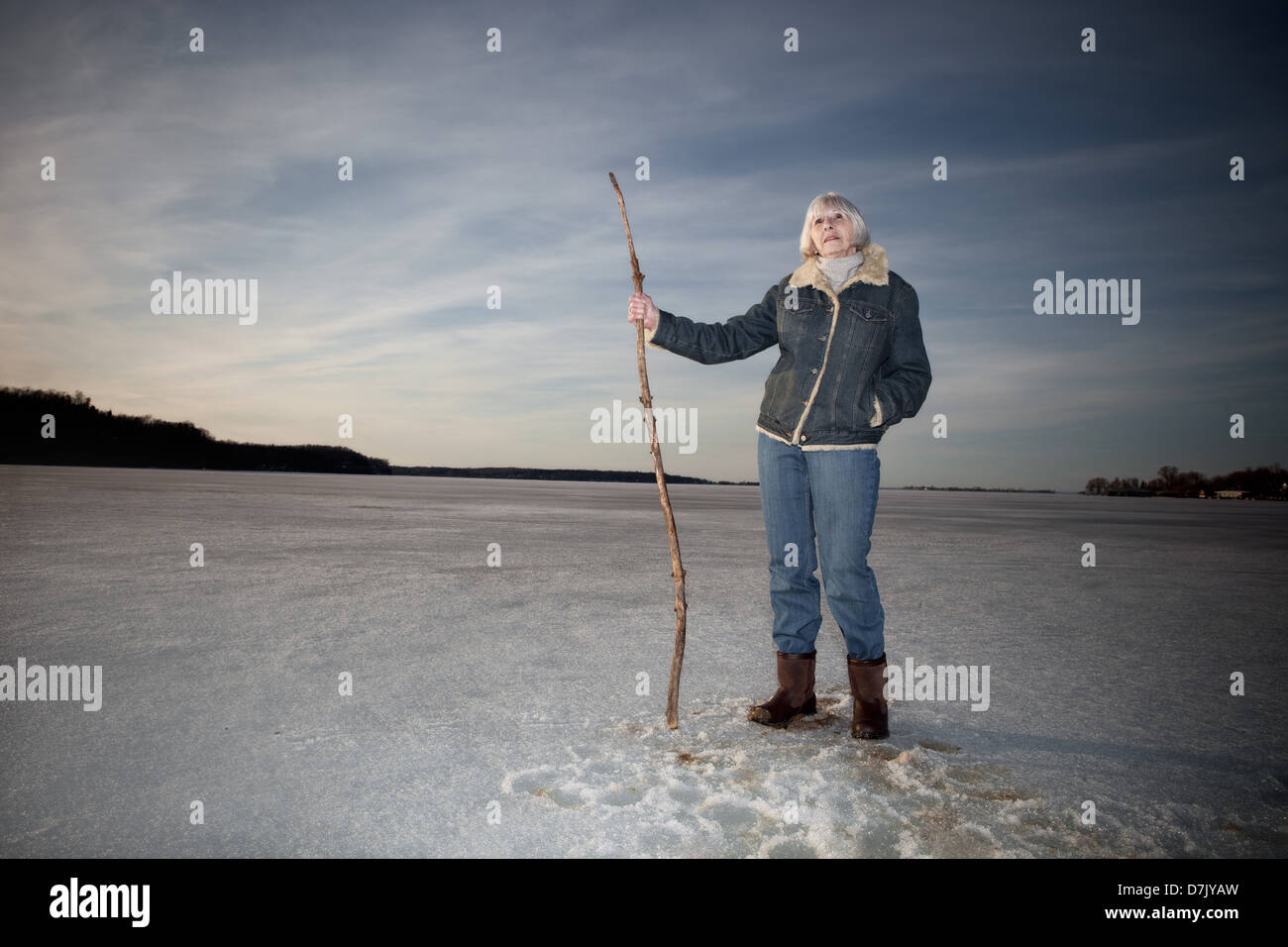 Environmental portrait of woman in her 70's standing on lake holding stick cane Stock Photo