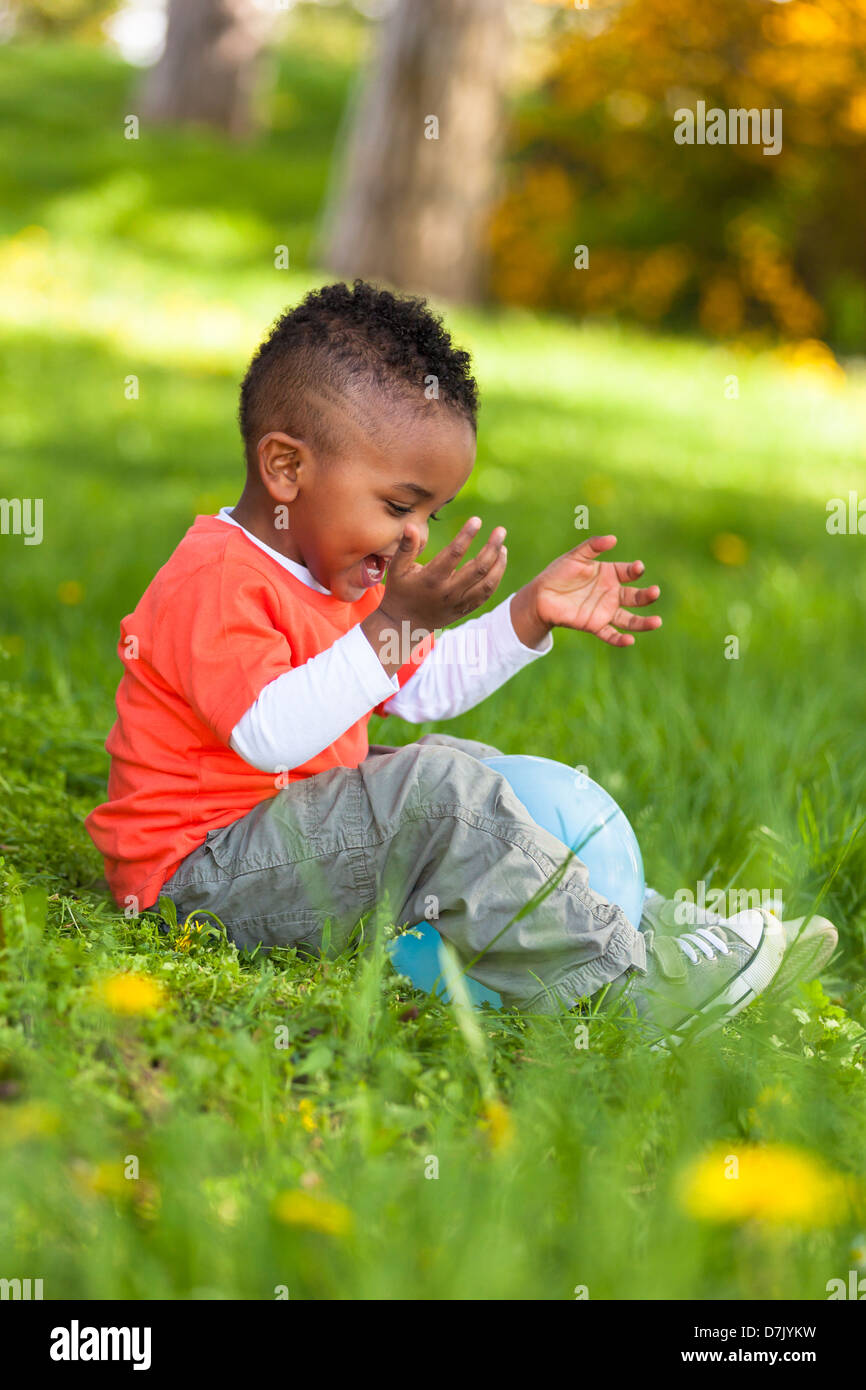 Outdoor portrait of a cute young little black boy playing with a