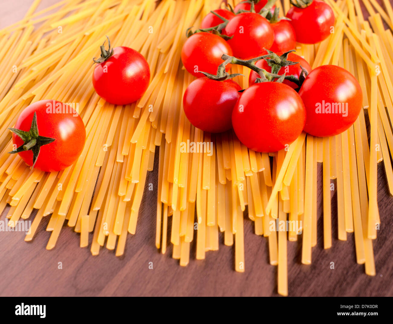 Raw spaghetti and cherry tomatoes on wooden table Stock Photo - Alamy