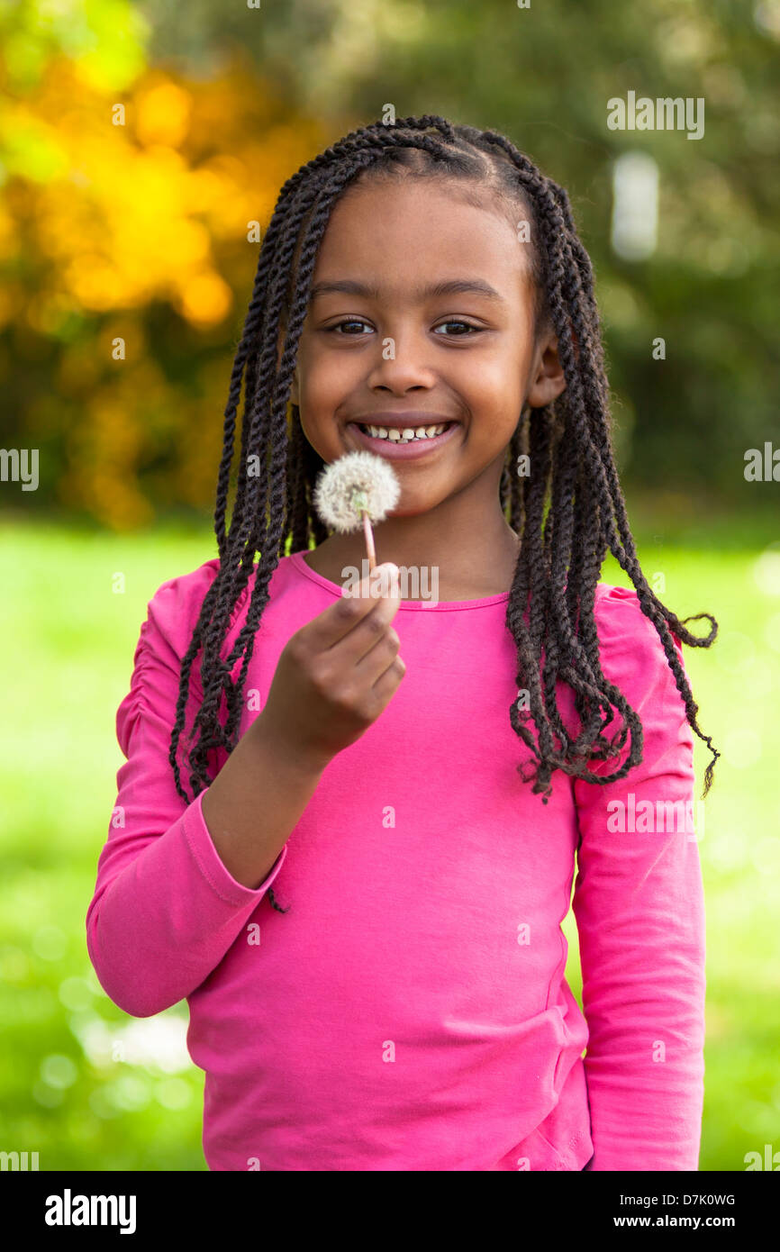 Outdoor Portrait Of A Cute Young Black Girl Holding A Dandelion