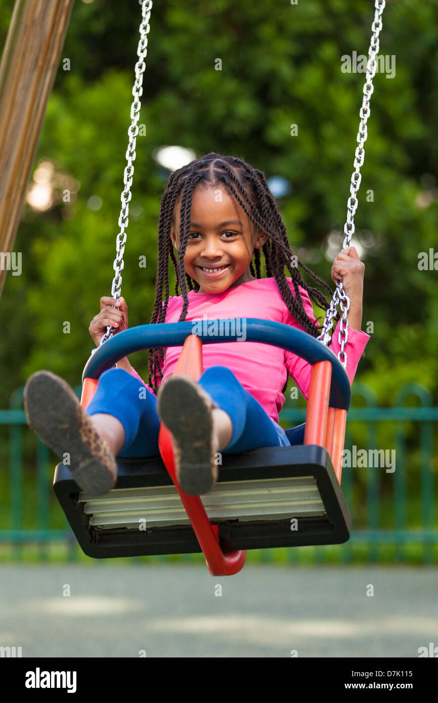 Outdoor portrait of a cute young black girl playing with a swing - African people Stock Photo