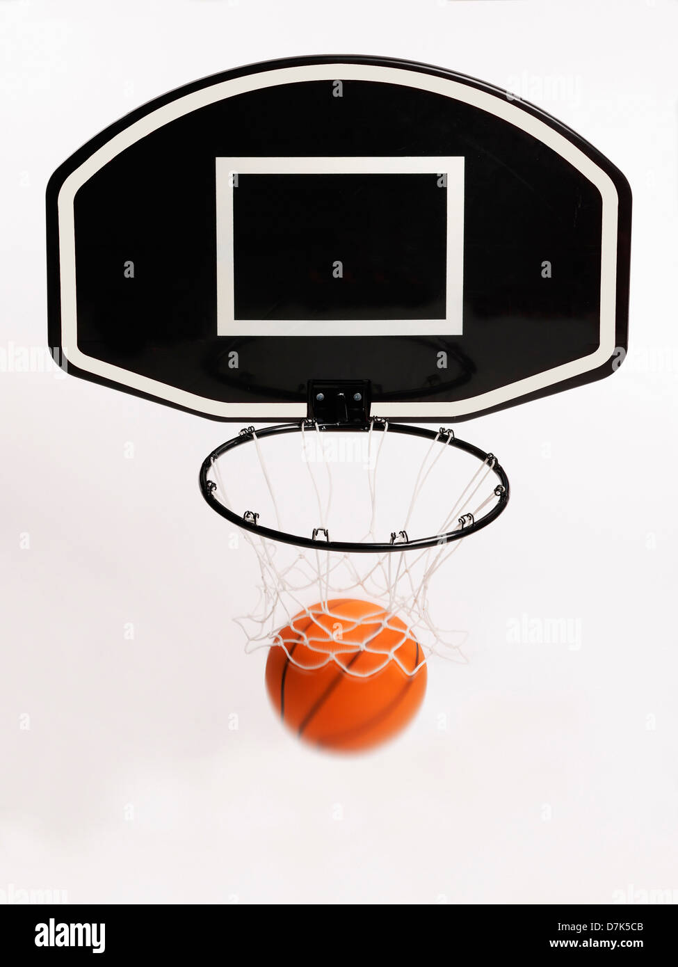 Basketball falling through hoop against white background Stock Photo