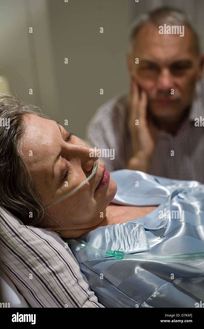 Dying old woman in hospital bed with caring man Stock Photo