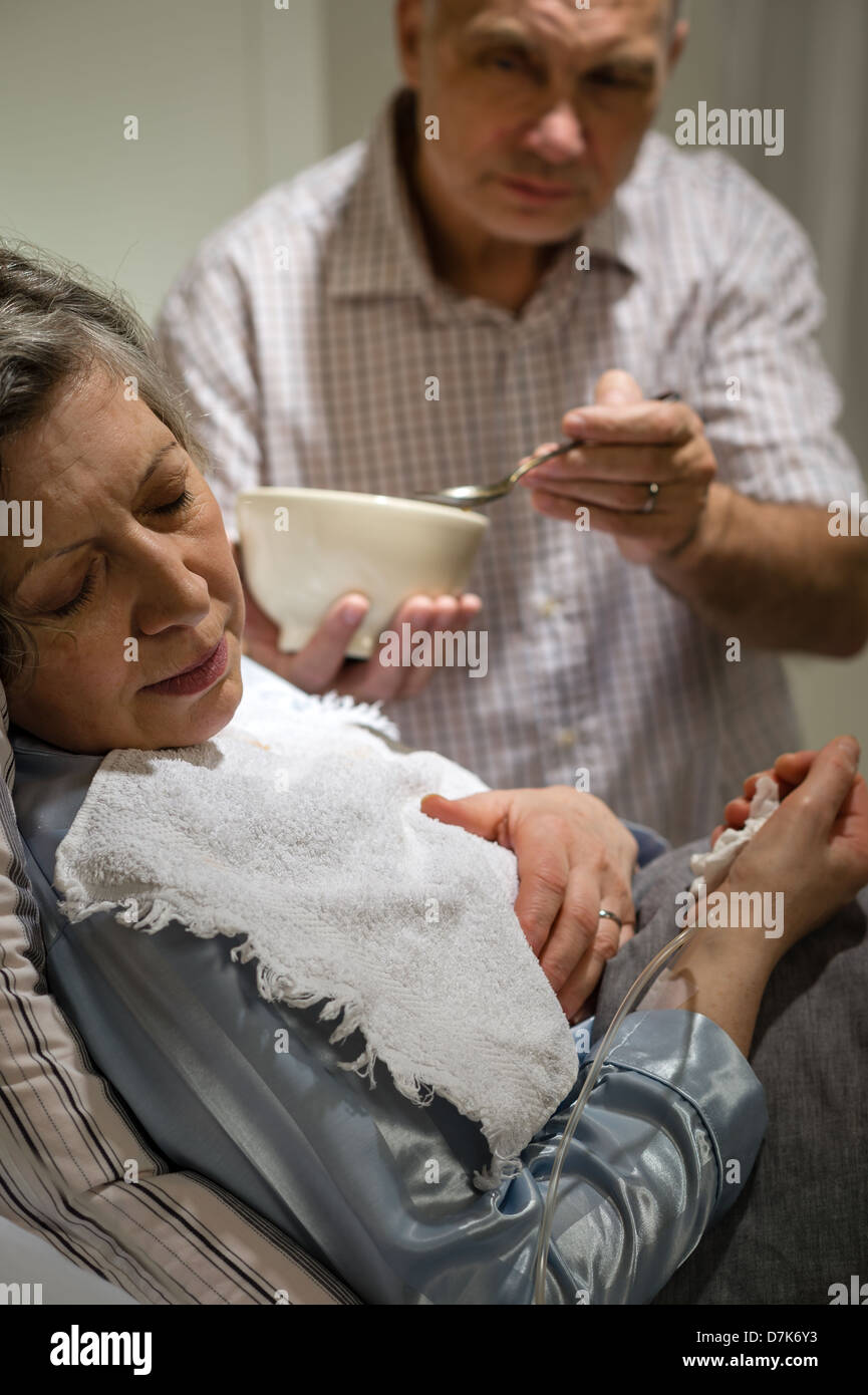 Mature man helping his ill wife feeding soup Stock Photo