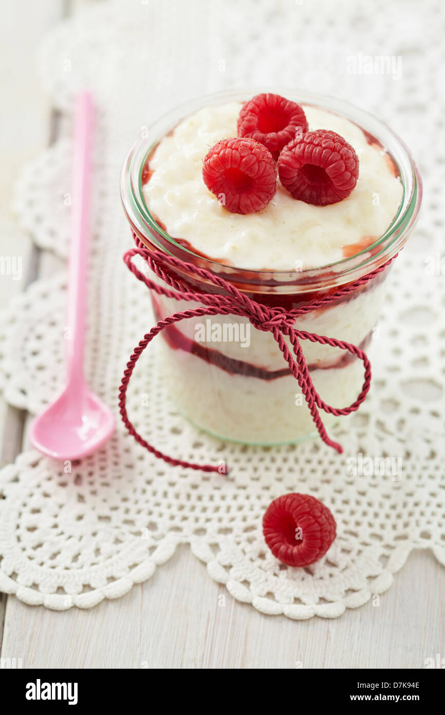 Milk rice pudding with raspberries and jam in glass on table Stock ...