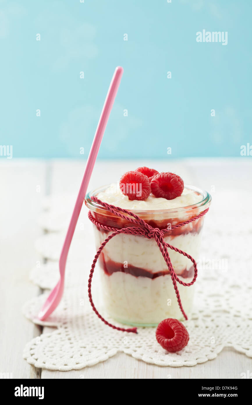 Milk rice pudding with raspberries and jam in glass on table Stock ...