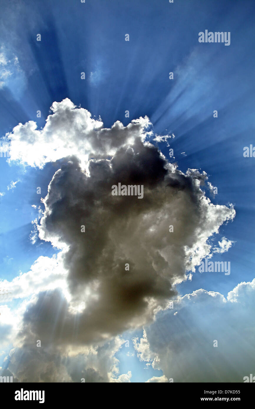 sun rays bursting through and around a cloud in the sky Stock Photo