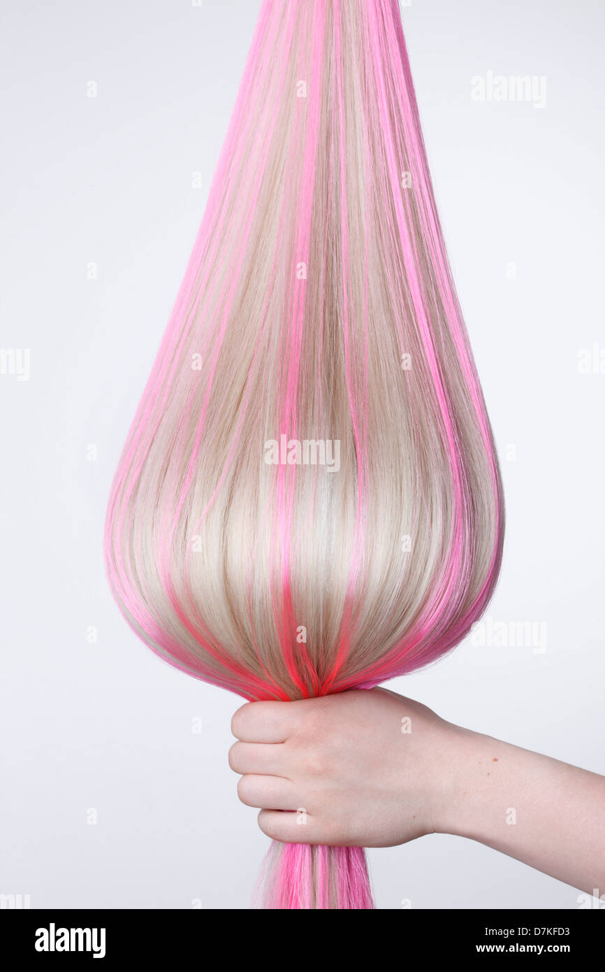 Human hand holding blond hair with pink highlights against white background, close up Stock Photo
