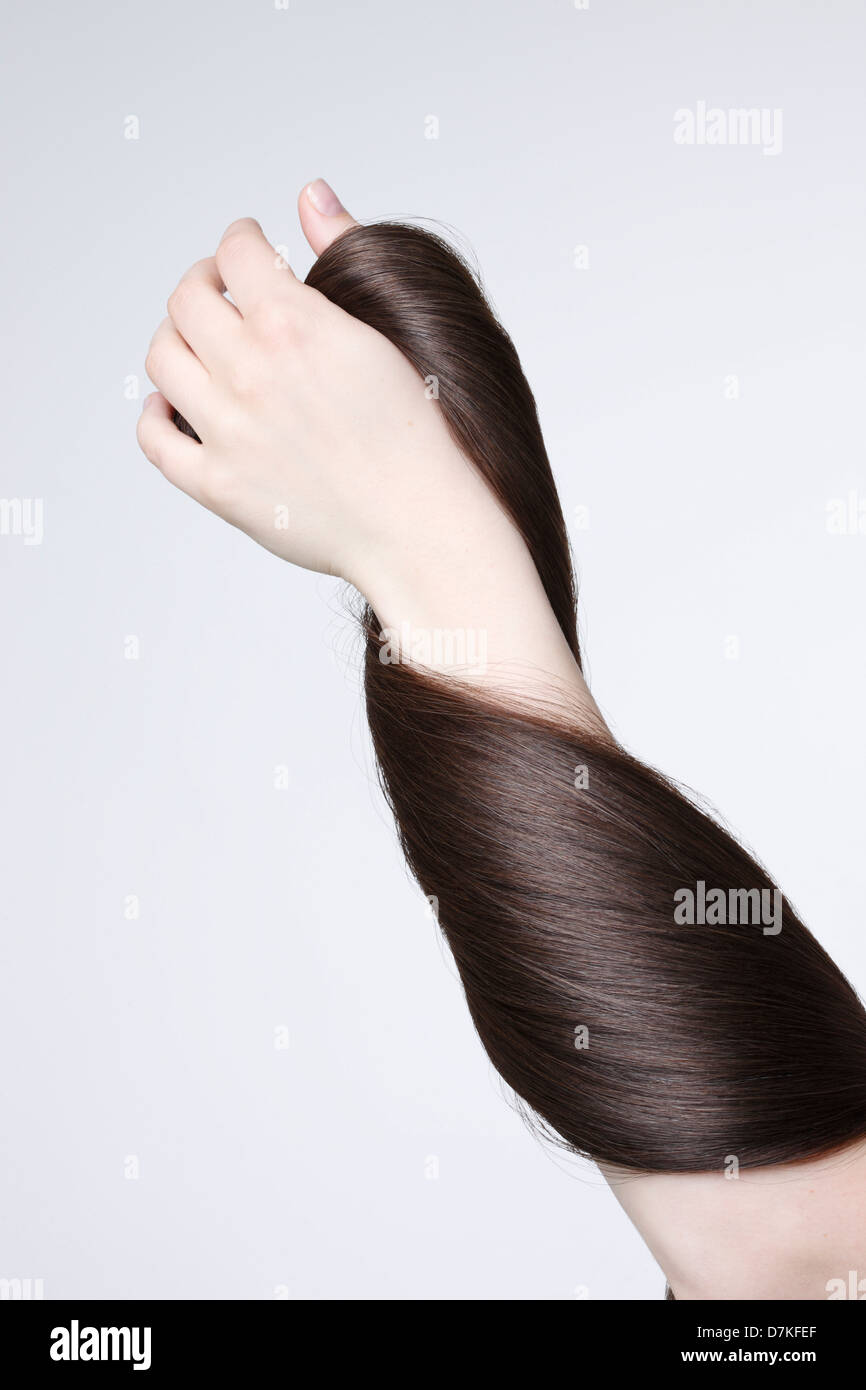 Human hand holding brown hair against white background, close up Stock Photo