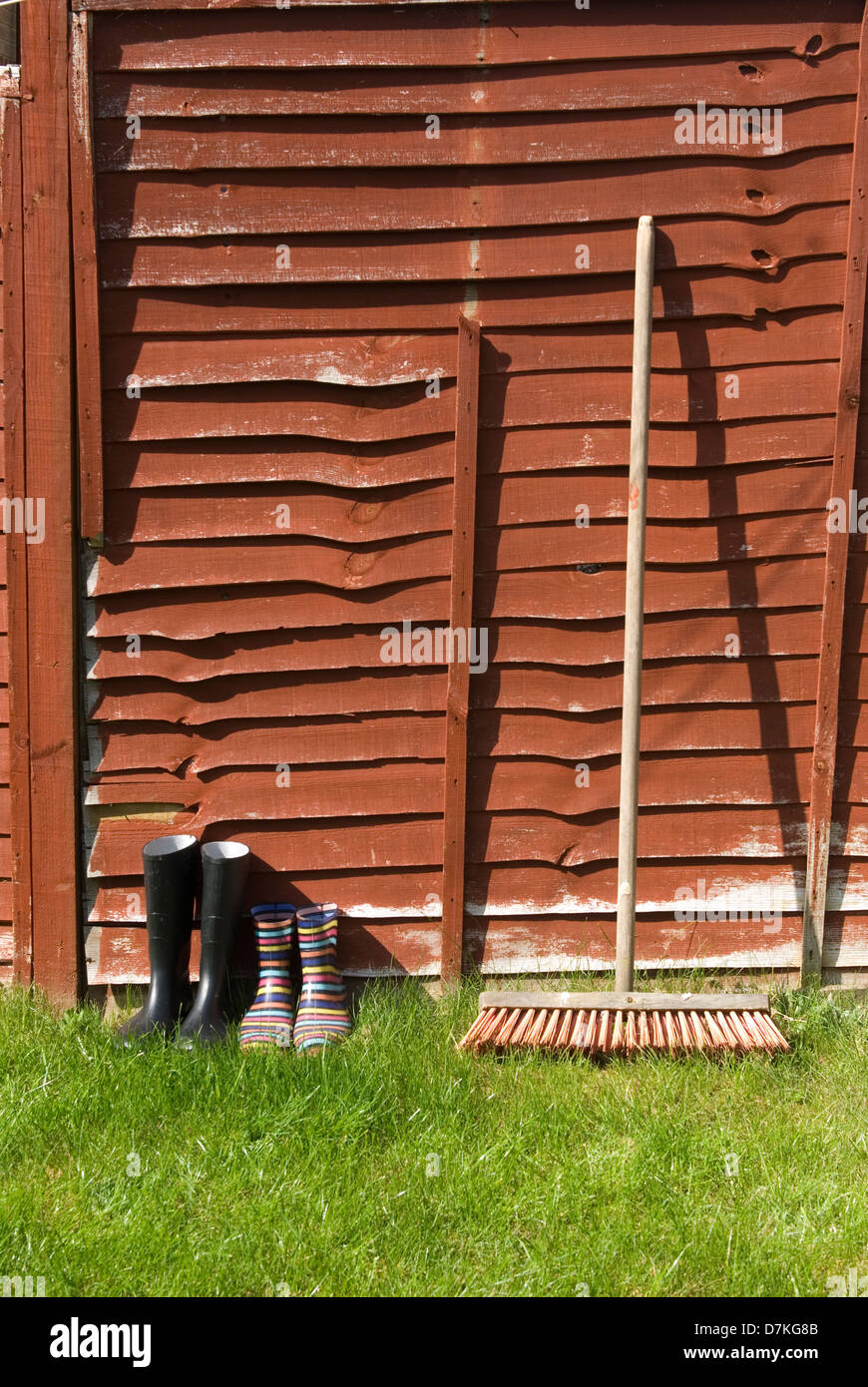 wellington boots drying against fence Stock Photo