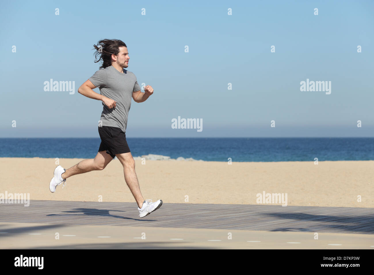 Sportsman running on the seafront of the beach with the sea in the background Stock Photo
