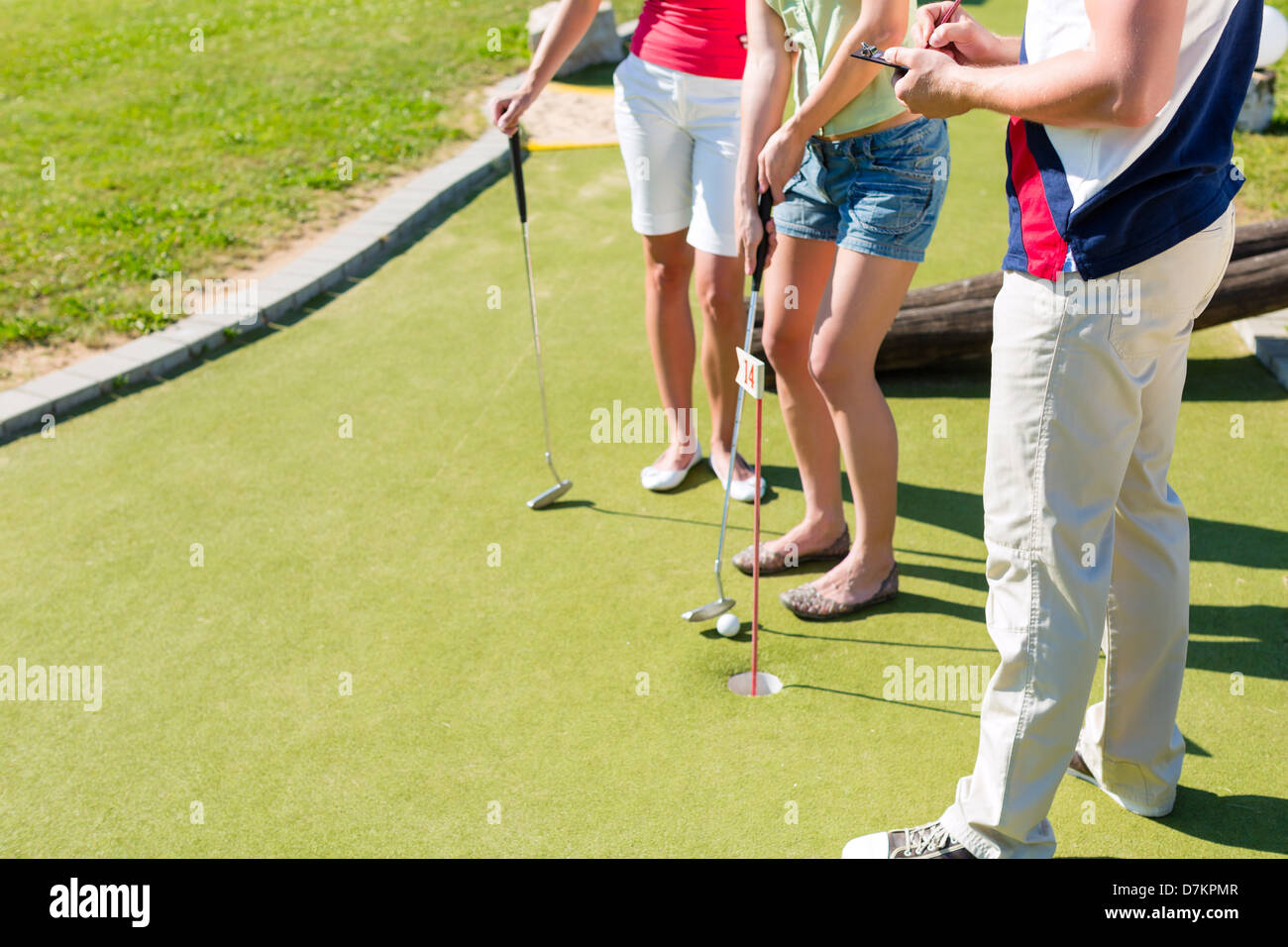 People, man and women, playing miniature golf on a beautiful summer day Stock Photo