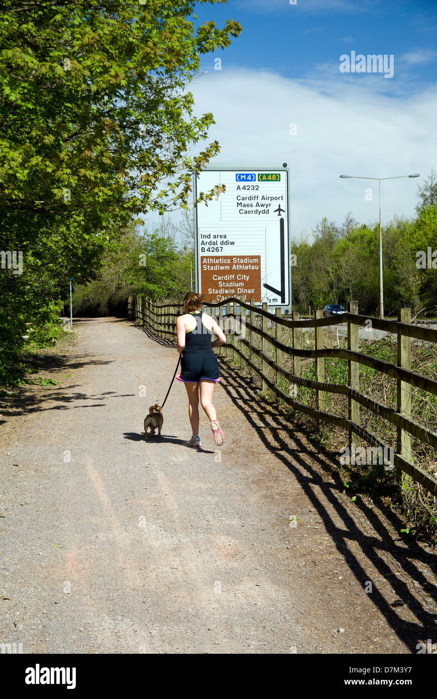 girl with dog running along ely trail besides A4232 grangetown link road cardiff wales Stock Photo