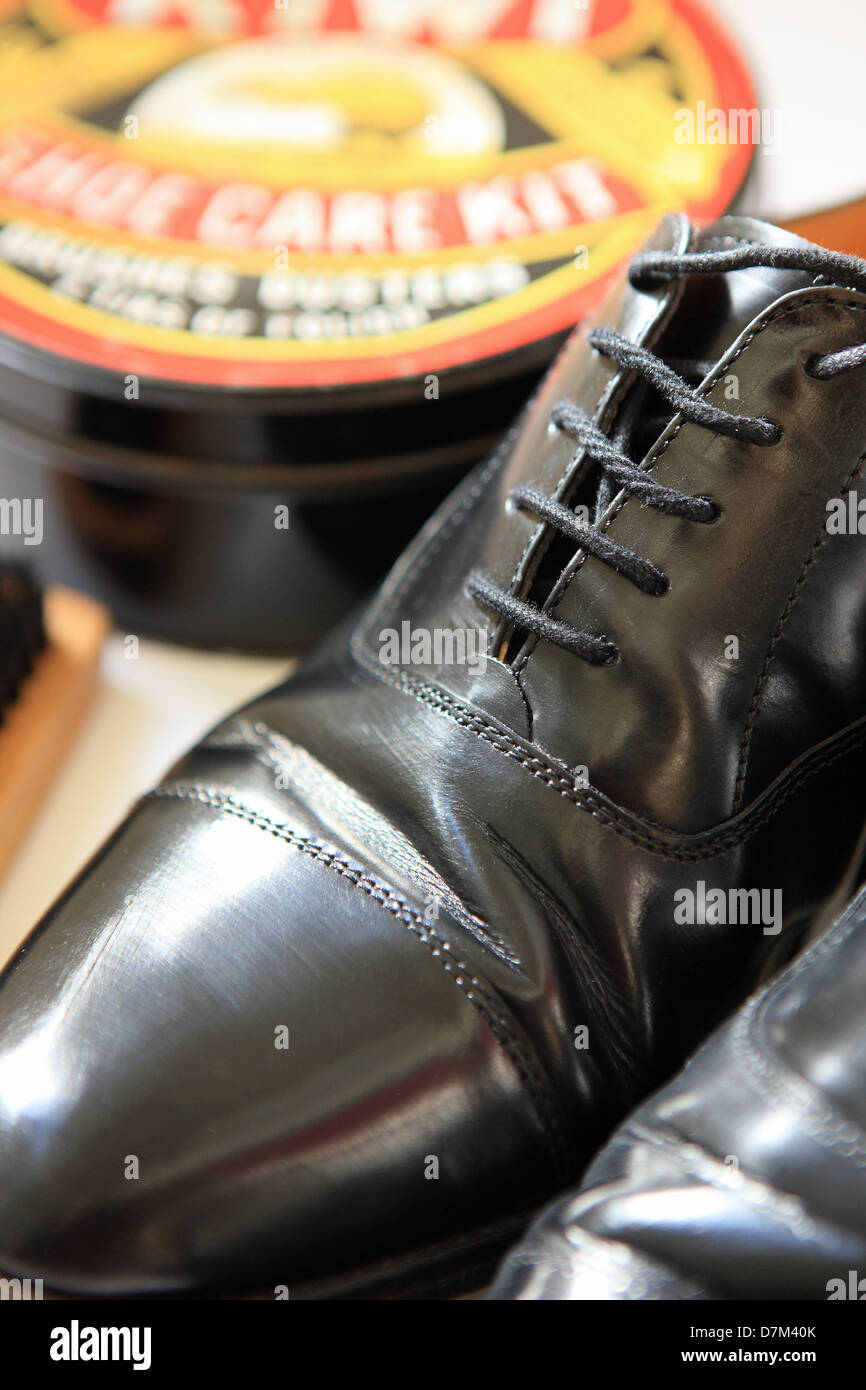 Polished pair of mens shoes with shoe care kit in the background Stock Photo