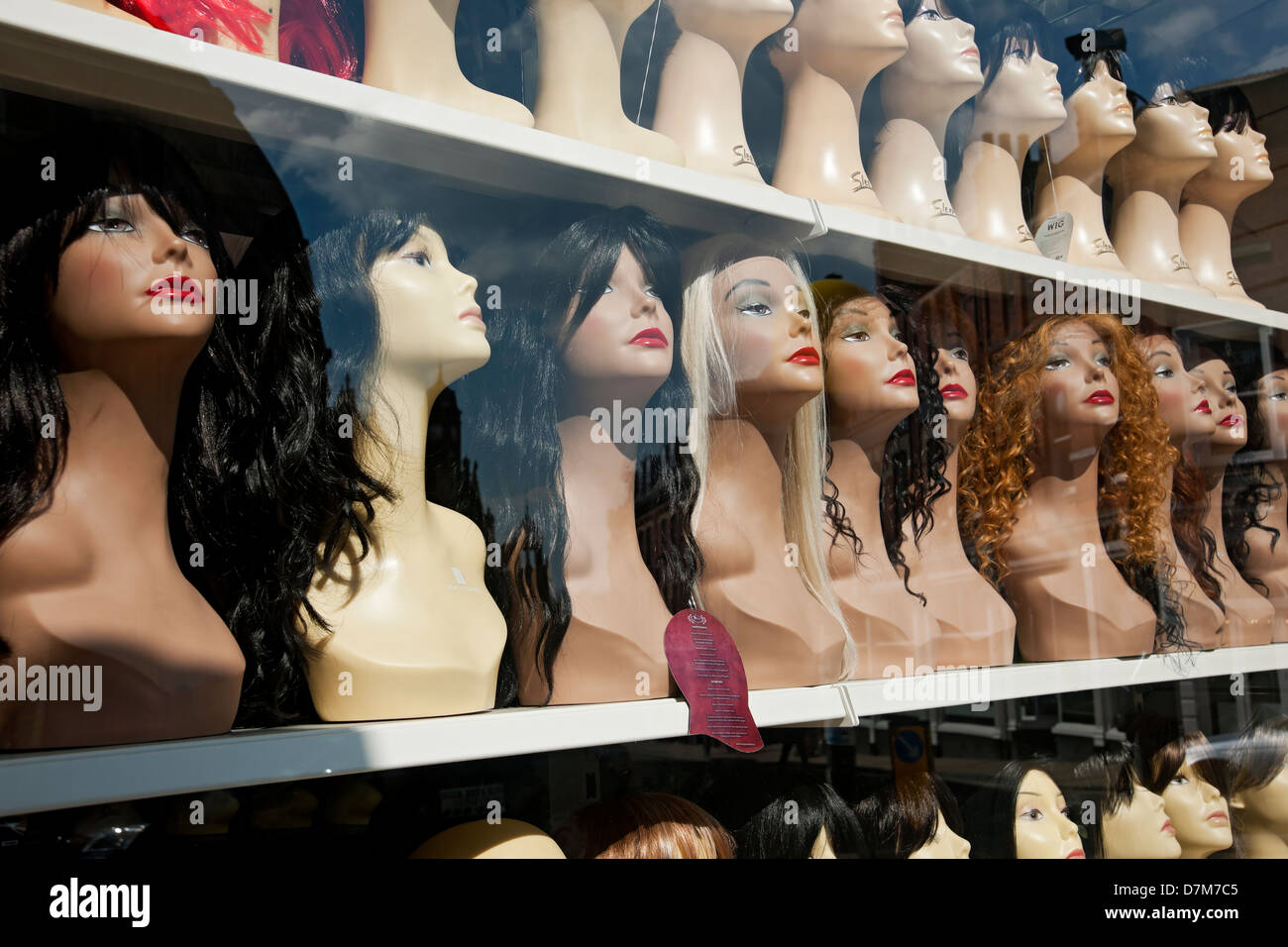 Female womens wigs on display in shop store window England UK United Kingdom GB Great Britain Stock Photo