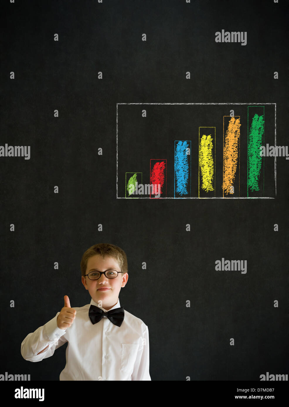 Thumbs up boy dressed up as business man with chalk graph or chart on blackboard background Stock Photo
