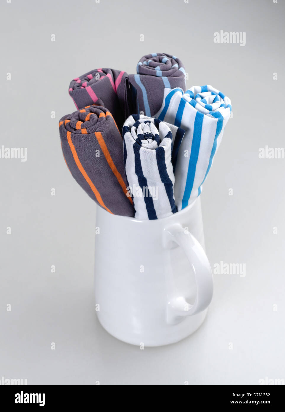 rolled colorful cotton t-shirts in a white jar Stock Photo
