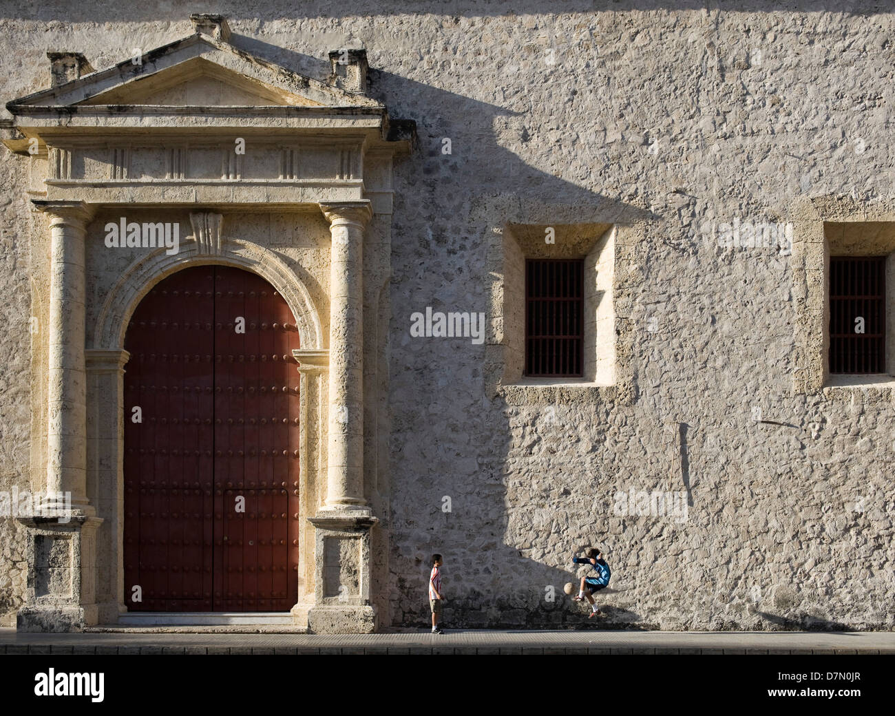 Boys playing football (soccer) by the side of the Cathedral, in the old city, Cartagena, Colombia Stock Photo