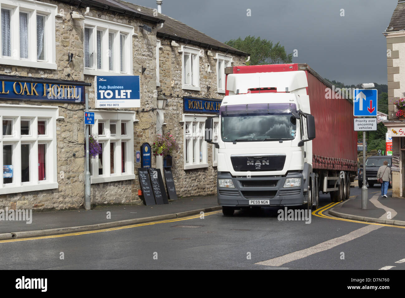An articulated lorry (HGV) negotiating the narrow road (B6480) which passes through the town centre of Settle in North Yorkshire Stock Photo