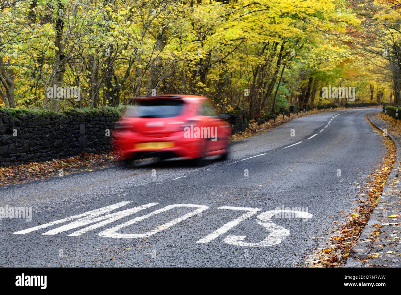 Motion blurred car travelling on a local country road in Autumn