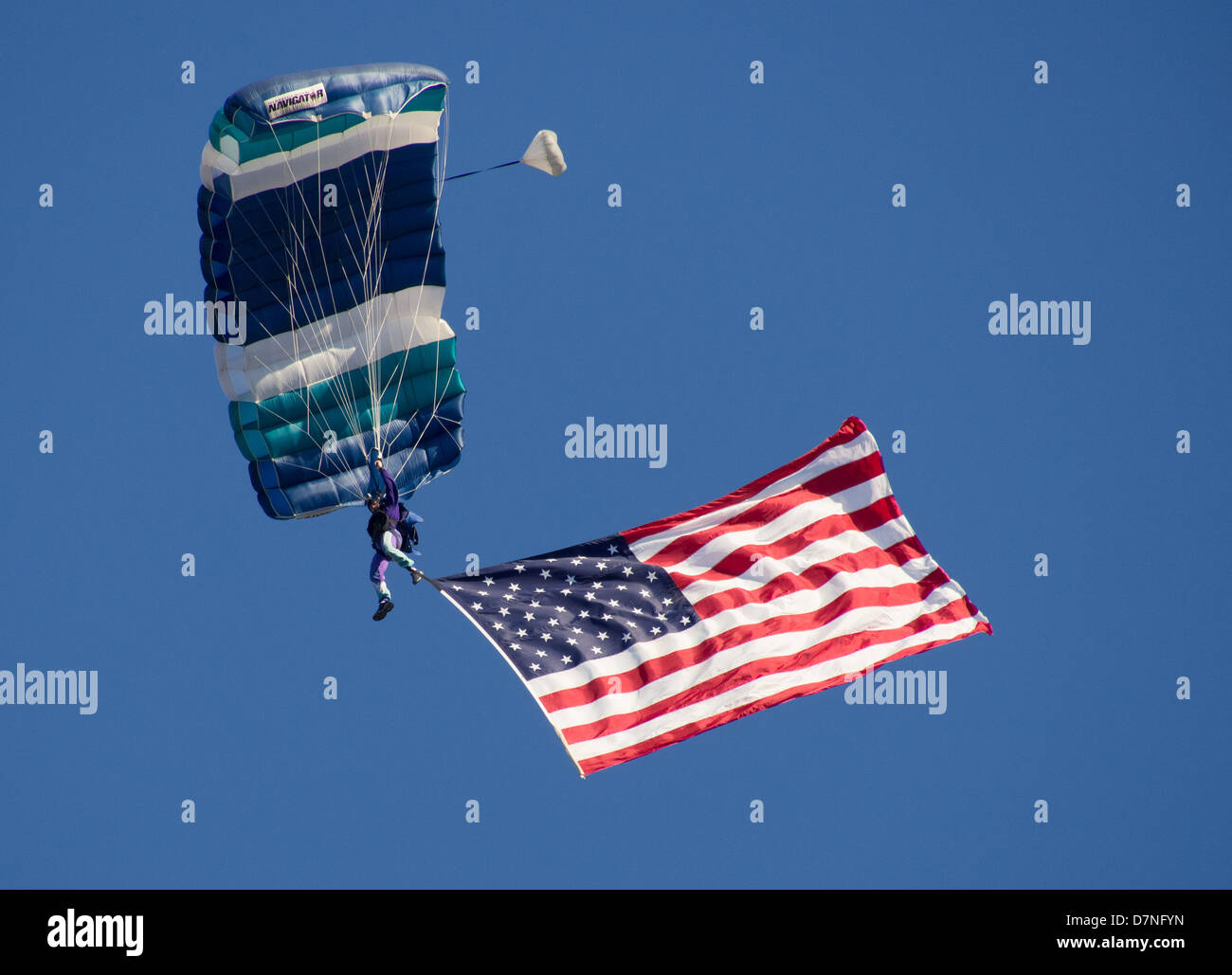 A skydiver with a giant American flag parachutes to the ground at the