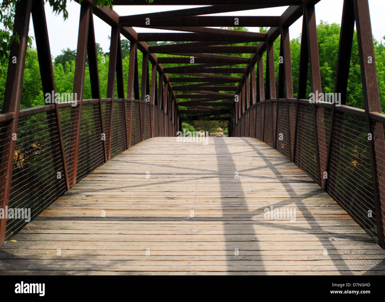 Arcing wood and metal frame bridge in park. Stock Photo