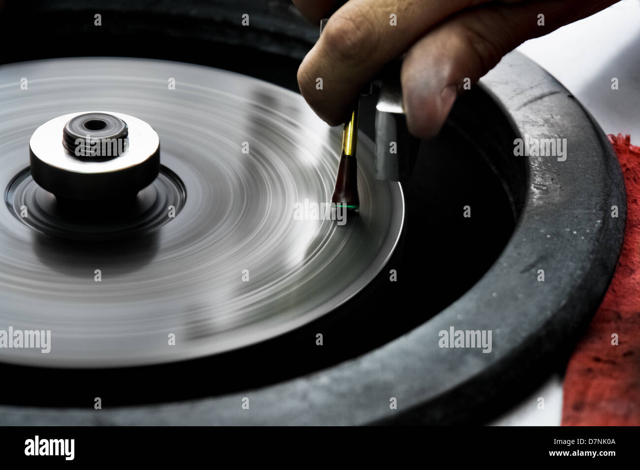 An emerald cutter polishes a gemstone on a faceting machine in a